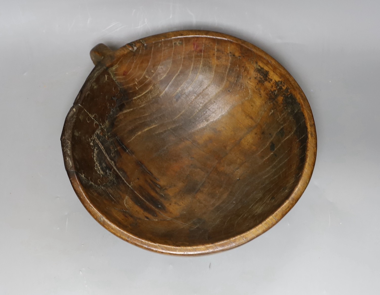 A carved elm mazer bowl, with old blacksmith repair, 31cm diameter